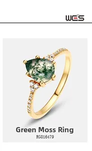 Macro shot of pear-shaped moss agate ring with gold band and side diamond accents