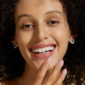 Détail de boucles d'oreilles en agate mousse carrée avec halo de diamants sur un mannequin