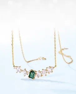 Macro shot of green moss agate necklace with emerald cut stone and gold chain detailing