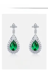 Vue détaillée des boucles d'oreilles émeraude poire avec halo de pierres blanches