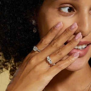 Close-up of S925 sterling silver moissanite rings and teardrop earrings on a model