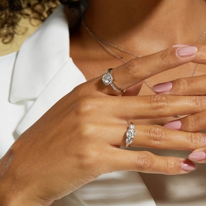 Close-up of S925 silver rings with halo and three-stone moissanite on model's hand