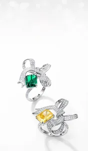 Detail of S925 silver bow rings with emerald green and yellow stones in micro pave setting