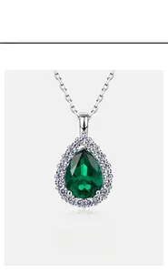 Close-up of a pear-shaped emerald pendant with a halo of white zircons on a silver chain