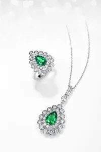 Macro detail of pear-cut lab emerald necklace and ring set with halo zircon stones