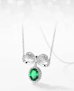 Vue macro du pendentif nœud en argent S925 avec émeraude ovale et halo de diamants