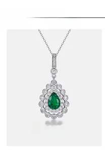 Macro shot of pear-shaped emerald pendant with brilliant circular cut diamonds set in silver