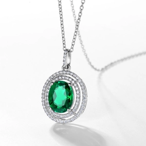 Oval emerald pendant necklace with double halo of white stones on a silver chain