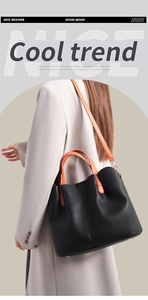 Close-up of black textured leather tote with vibrant orange handles and shoulder strap