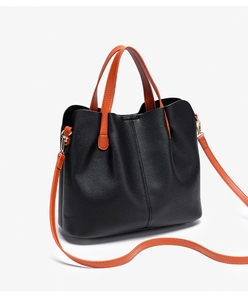 Detail of black lychee grain leather tote bag with contrasting orange handles and hardware