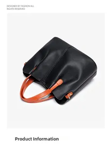 Detail view of black lychee grain leather tote bag with contrasting orange handles