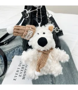 Détail d'un ours en peluche blanc avec bonnet et écharpe marron sur un sac en cuir noir