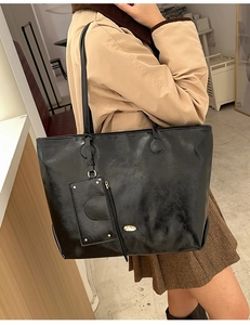 Detail of black oil wax leather tote bag with small detachable pouch and gold logo