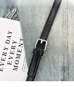 Détail d'une bandoulière réglable en cuir noir avec boucle argentée pour sac à main