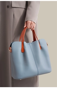 Detail of light blue lychee pattern leather briefcase with orange handles and metal feet