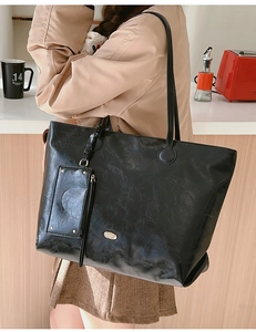 Detail of black wax texture tote bag with matching inner pouch on a cafe table