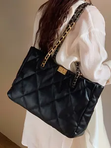 Detail of classic black quilted tote bag with gold chain strap and elegant turn-lock closure