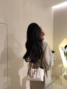 Détails du sac seau en cuir blanc avec foulard en soie et fermoir doré chic