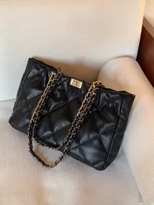 Close-up of black quilted leather tote bag featuring gold twist lock and chain strap