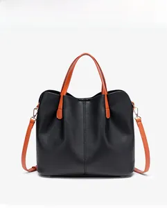 Detailed close-up of black lychee grain texture with orange handles and gold metal hardware