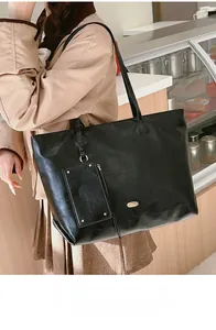 Close-up of black tote bag with smooth texture and stylish gold logo detail