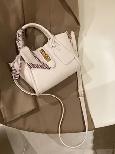 Détail d'un sac cabas en cuir blanc avec fermoir doré et foulard en soie pied-de-poule