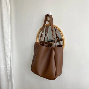 Detail of dark brown leather tote bag with unique metal rivet buckle on the shoulder strap