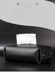 Detail of black leather tissue box featuring matte texture and metal rivet fasteners