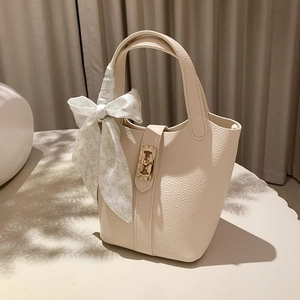 Detail of cream bucket bag with lychee texture and floral silk scarf on handle