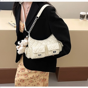 Détail du sac à bandoulière matelassé crème avec poches multiples et breloque ours en peluche