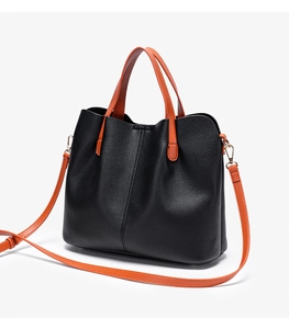 Close-up of litchi pattern leather with orange handles and golden metal hardware
