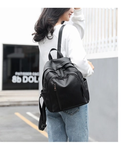 Close-up of black litchi pattern leather backpack showing large capacity and side pocket