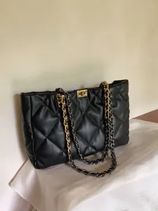 Detailed view of black quilted leather tote with gold-tone chain and metal lock