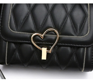 Détail du sac à bandoulière matelassé noir avec fermoir doré en forme de cœur chic