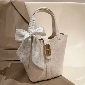 Detail of lychee pattern leather bucket bag with gold twist lock and floral scarf handle
