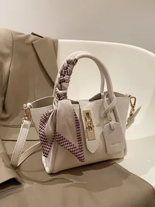 Détail du sac à main blanc en cuir litchi avec fermoir doré et foulard en soie pied-de-poule