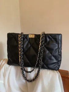 Detail of black quilted tote bag with gold metal twist lock and diamond stitching