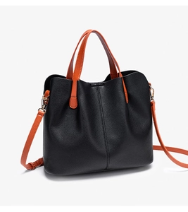 Close-up of black lychee grain texture and vibrant orange handles on a tote briefcase