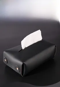 Close-up of a modern black PU leather tissue box with metal rivets on a minimalist dark background