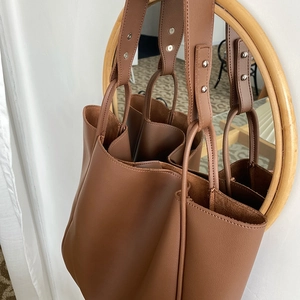 Detail view of large brown leather tote bag showing silver rivets and soft texture