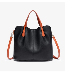 Close-up of black litchi grain leather tote with contrast orange handle and gold hardware