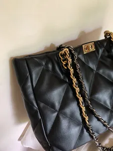 Close-up of black quilted leather tote with dual-tone metal chain and gold twist lock