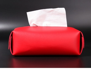 Close-up of red leather tissue box with side metal snap button and white tissue inside