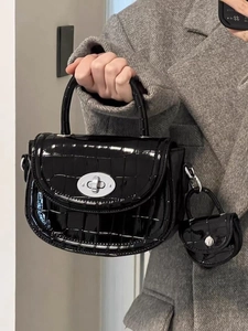Détail d'un sac à main en cuir verni noir gaufré croco avec fermoir tournant argenté