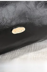 Close-up of black retro textured leather bag featuring a gold irregular metal buckle