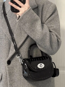 Détail du sac selle noir en cuir verni façon crocodile avec fermoir rotatif argenté