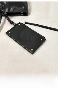Detail of black glossy leather pouch with metal studs and elegant golden buckle