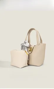 Detail of off-white lychee grain bucket bag set with silk scarf and gold lock hardware