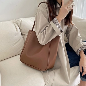 Detailed side view of a large brown leather tote bag worn on shoulder for commuting