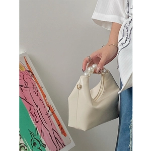 Detail of elegant pearl handle handbag in creamy white with smooth leather texture